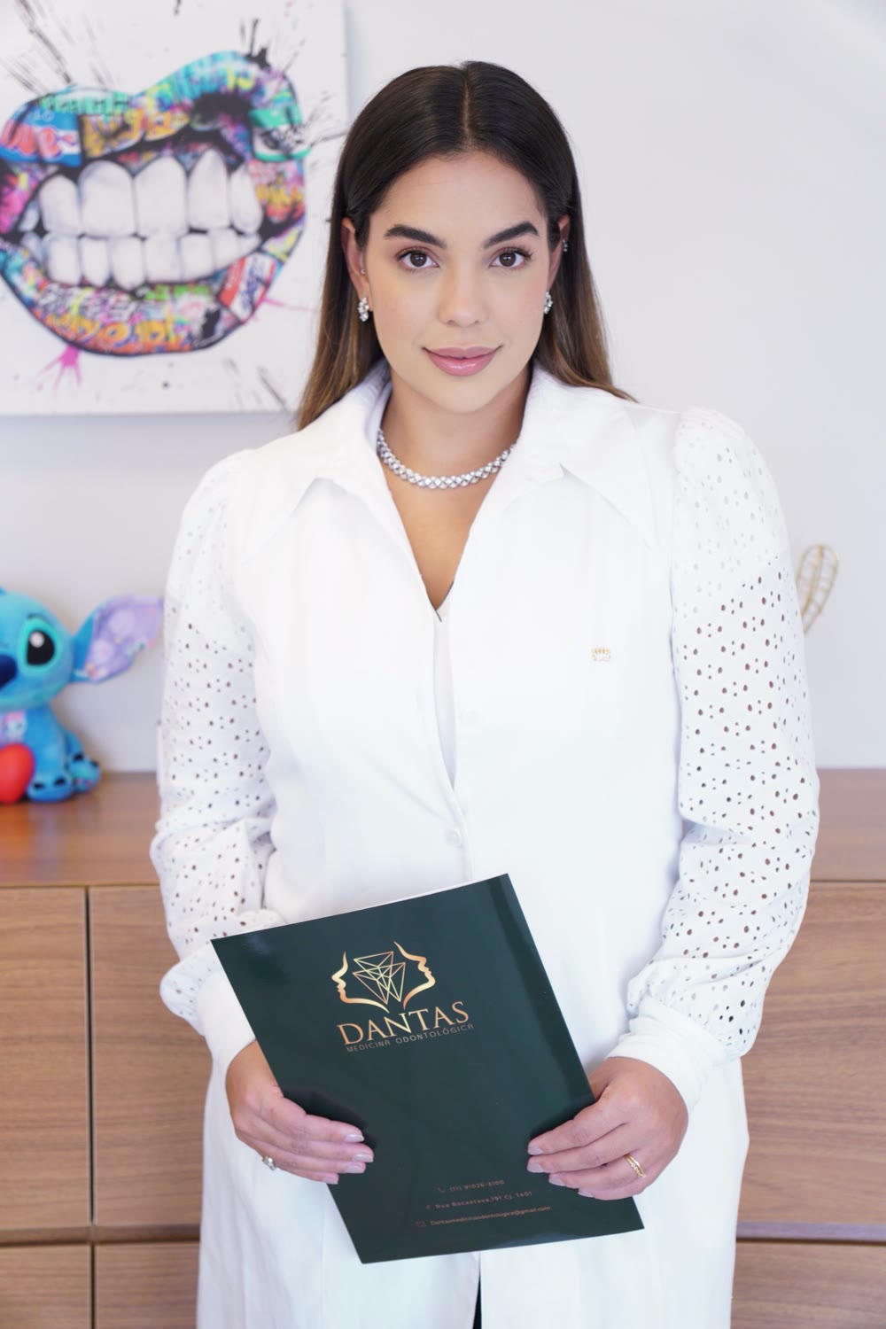 Dra. Larissa Dantas de jaleco segurando a pasta da clínica